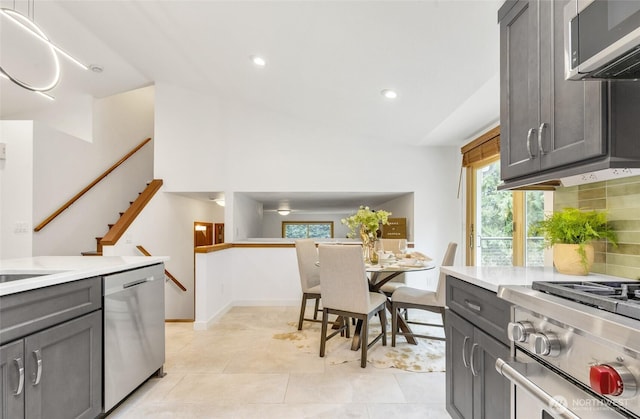 kitchen featuring light tile patterned floors, gray cabinets, stainless steel appliances, decorative backsplash, and light countertops