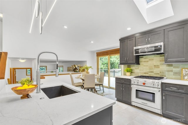 kitchen with a sink, light stone counters, backsplash, and stainless steel appliances