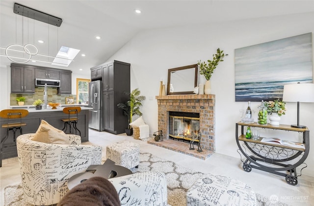 living room featuring a brick fireplace, vaulted ceiling with skylight, and recessed lighting