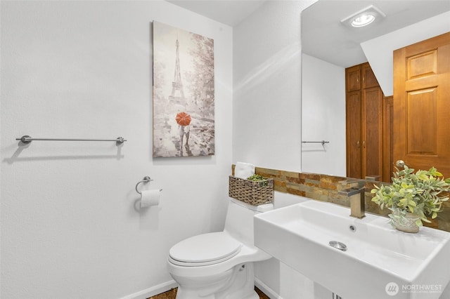 bathroom featuring toilet, baseboards, and a sink