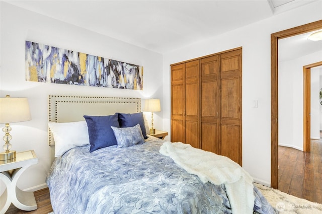 bedroom with wood finished floors, a closet, and baseboards