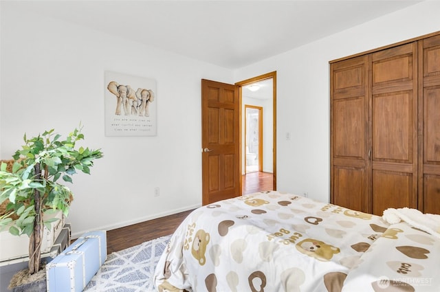 bedroom featuring wood finished floors, baseboards, and a closet