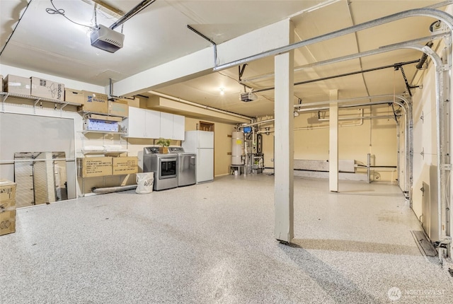 garage featuring water heater, independent washer and dryer, a garage door opener, and freestanding refrigerator