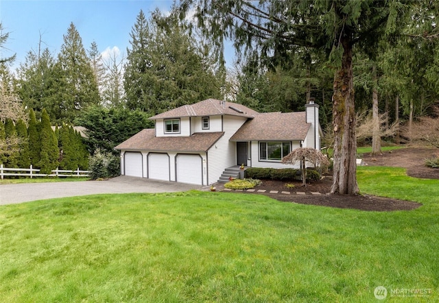 split level home featuring driveway, fence, an attached garage, a front yard, and a chimney