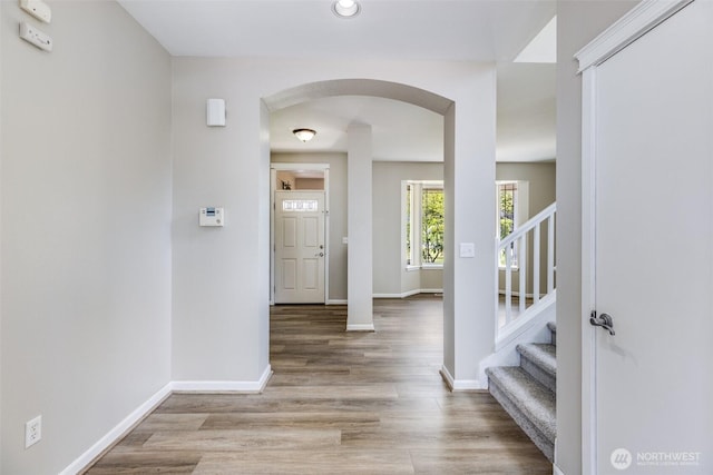 entryway featuring stairs, wood finished floors, arched walkways, and baseboards