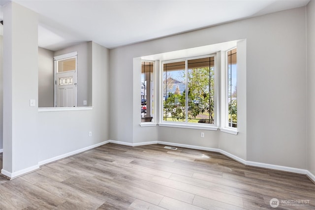 spare room featuring visible vents, wood finished floors, and baseboards