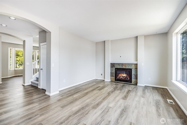 unfurnished living room with visible vents, plenty of natural light, and wood finished floors