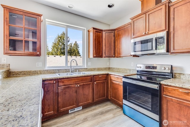 kitchen featuring light wood finished floors, visible vents, light countertops, stainless steel appliances, and a sink