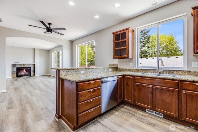 kitchen featuring light stone counters, visible vents, a premium fireplace, a sink, and dishwasher