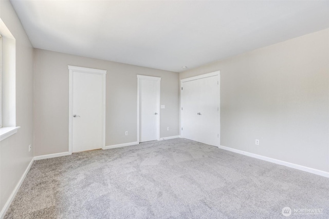 unfurnished bedroom with baseboards, carpet, and multiple closets