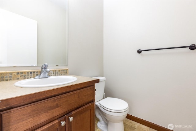 bathroom featuring toilet, vanity, and baseboards