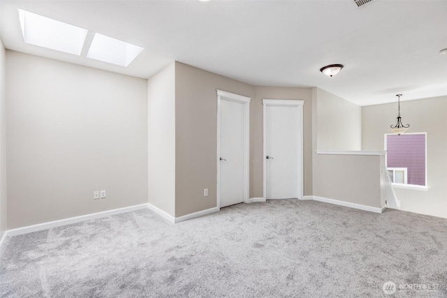 carpeted empty room featuring baseboards and a skylight