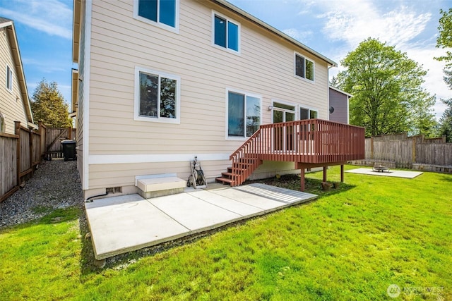 rear view of property with a fenced backyard, a deck, a lawn, and a patio