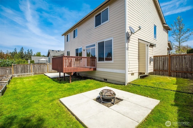 rear view of house featuring a yard, a fenced backyard, a fire pit, and a deck