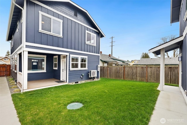 rear view of property with a fenced backyard, board and batten siding, a wall mounted air conditioner, and a lawn