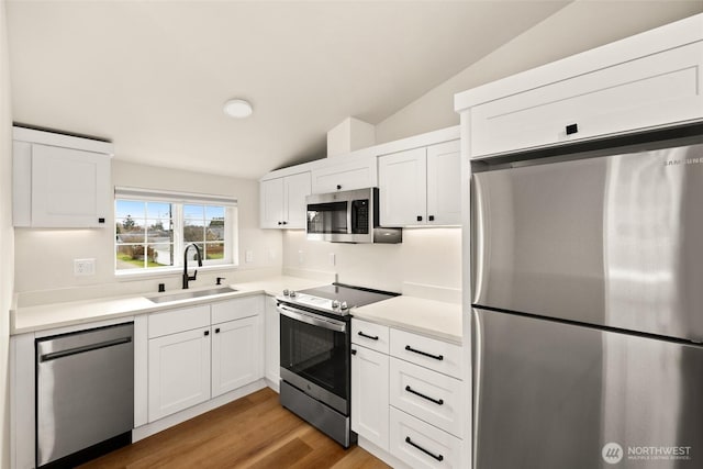 kitchen featuring a sink, white cabinetry, appliances with stainless steel finishes, and vaulted ceiling