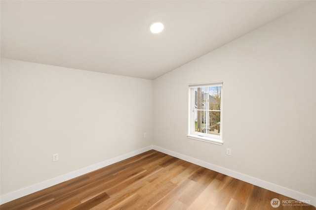 spare room featuring vaulted ceiling, wood finished floors, and baseboards