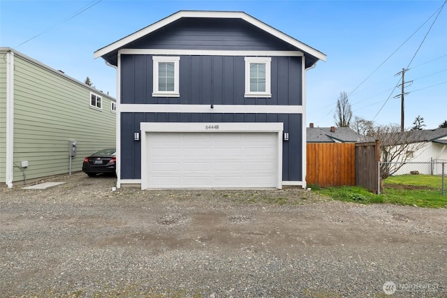 exterior space with a garage, board and batten siding, driveway, and fence