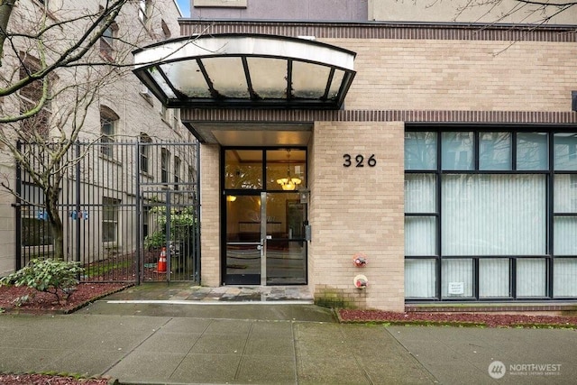 doorway to property featuring brick siding and fence