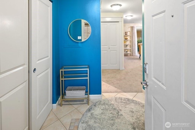 corridor with light tile patterned flooring, light colored carpet, and baseboards