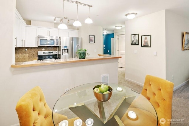 dining room featuring visible vents, light carpet, and baseboards