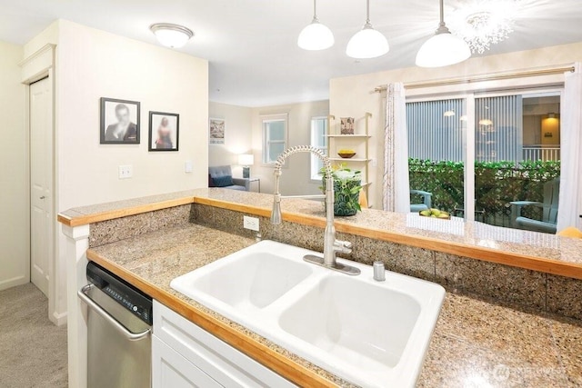 kitchen with carpet, a sink, white cabinets, stainless steel dishwasher, and decorative light fixtures