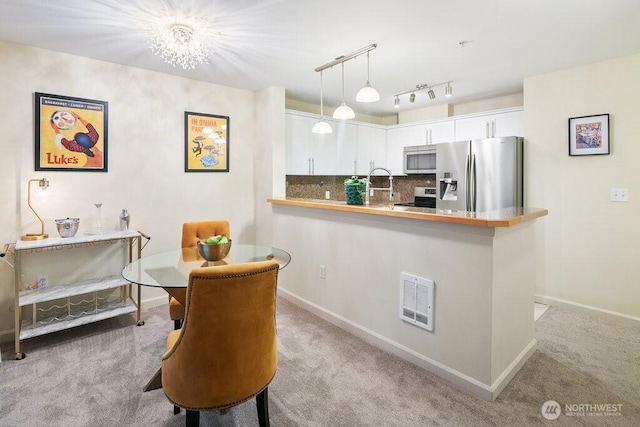 kitchen featuring visible vents, a sink, stainless steel appliances, white cabinetry, and light colored carpet