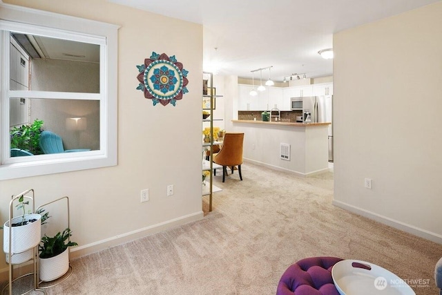 interior space featuring rail lighting, baseboards, and light carpet