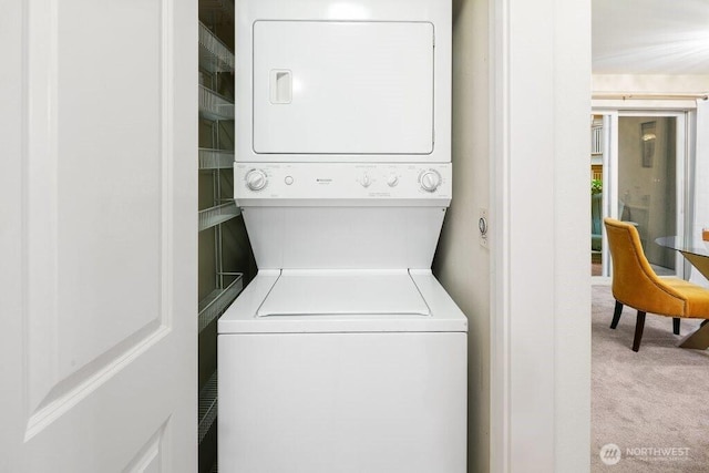 clothes washing area featuring stacked washer / drying machine, carpet, and laundry area