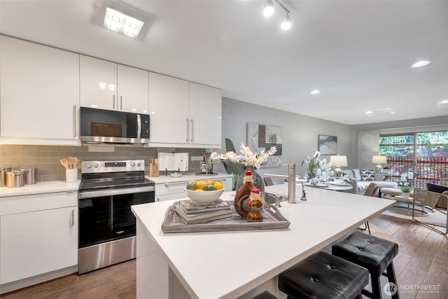 kitchen with backsplash, appliances with stainless steel finishes, light countertops, and wood finished floors