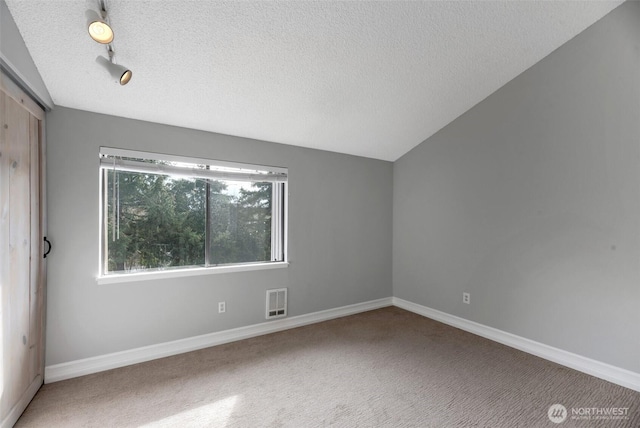 carpeted spare room featuring rail lighting, visible vents, baseboards, and a textured ceiling