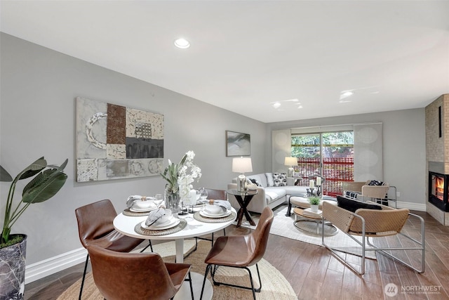 dining room with recessed lighting, wood finished floors, baseboards, and a large fireplace