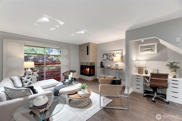 living area featuring a multi sided fireplace, baseboards, and wood finished floors