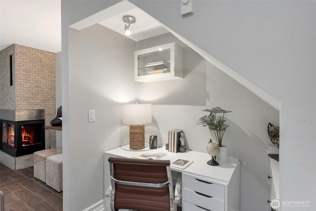 office area featuring wood finish floors, baseboards, and a fireplace