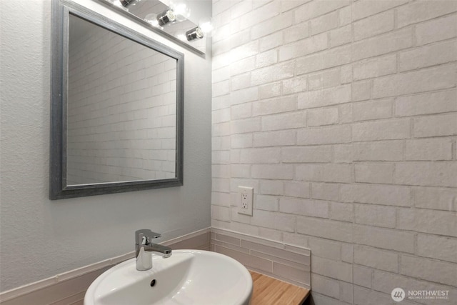 bathroom featuring a textured wall and a sink