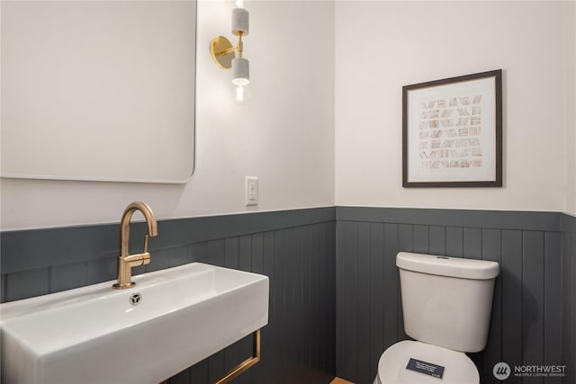 bathroom with wainscoting, toilet, and a sink