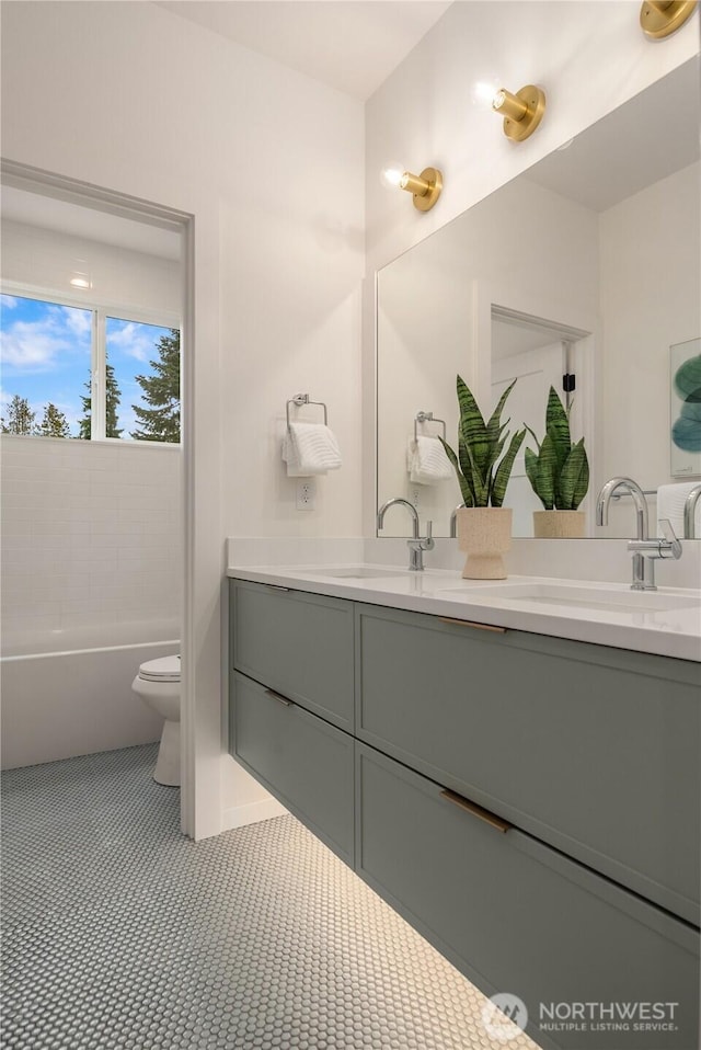 bathroom with double vanity, toilet, tile patterned floors, and a sink