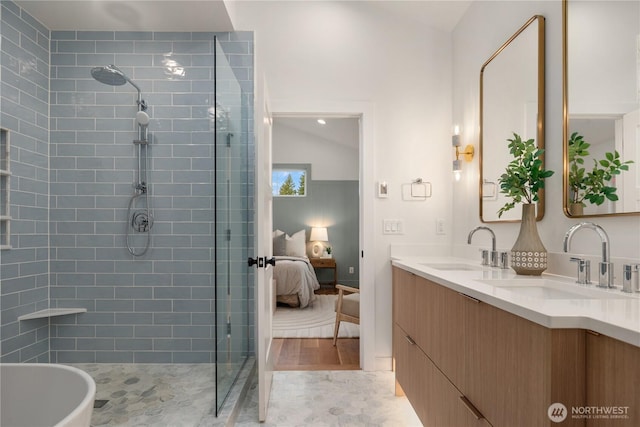 ensuite bathroom with a tile shower, connected bathroom, double vanity, and a sink