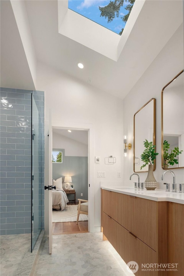 ensuite bathroom featuring tiled shower, double vanity, a sink, ensuite bathroom, and lofted ceiling with skylight