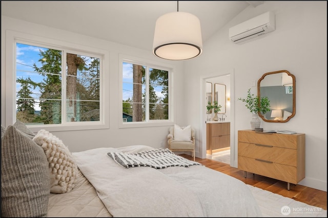 bedroom with an AC wall unit, wood finished floors, and connected bathroom