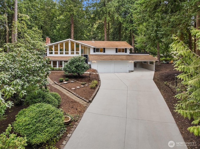 view of front of property with a garage, concrete driveway, and a chimney