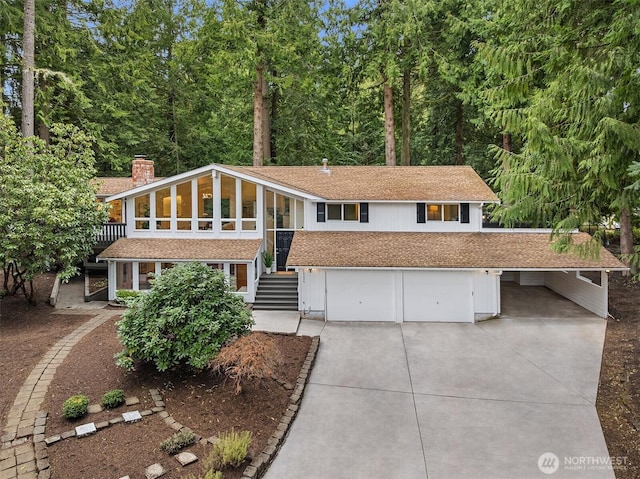 view of front of property featuring a garage, concrete driveway, and a chimney