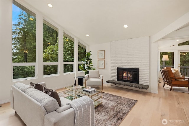 living area with recessed lighting, light wood-style flooring, a large fireplace, and baseboards