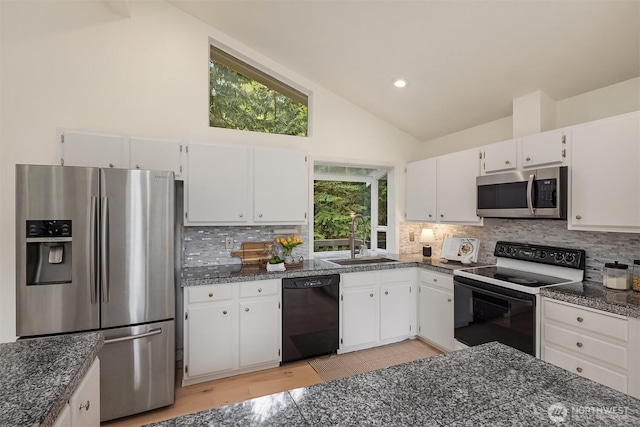 kitchen featuring vaulted ceiling, white cabinetry, stainless steel appliances, and a sink