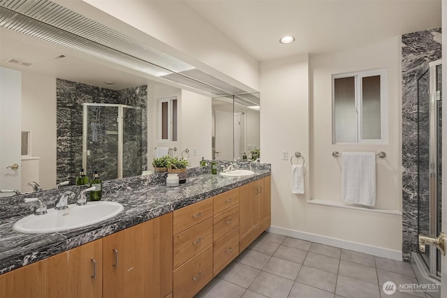 full bathroom featuring tile patterned flooring, double vanity, a stall shower, and a sink