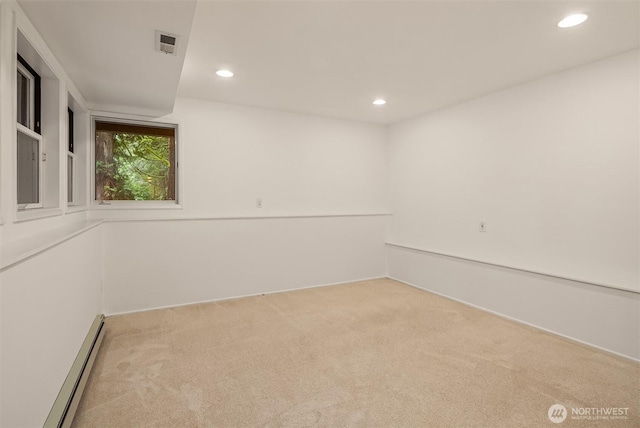 empty room with recessed lighting, a baseboard heating unit, light colored carpet, and visible vents