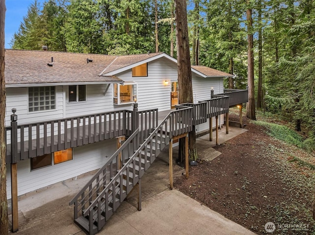 back of property featuring a deck, stairs, and a shingled roof