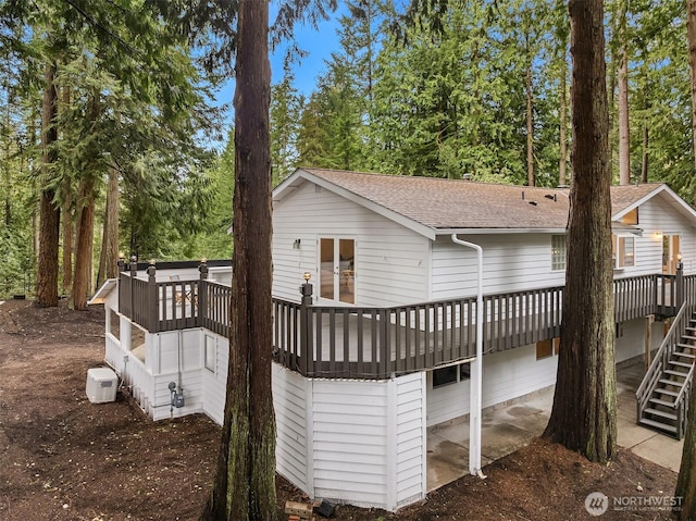 rear view of house with a wooden deck, stairway, and a shingled roof