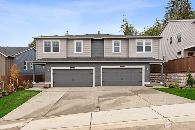 view of front of home featuring concrete driveway, roof with shingles, a garage, and fence