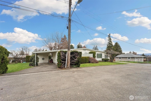 view of front of house with an attached carport, concrete driveway, and a front lawn